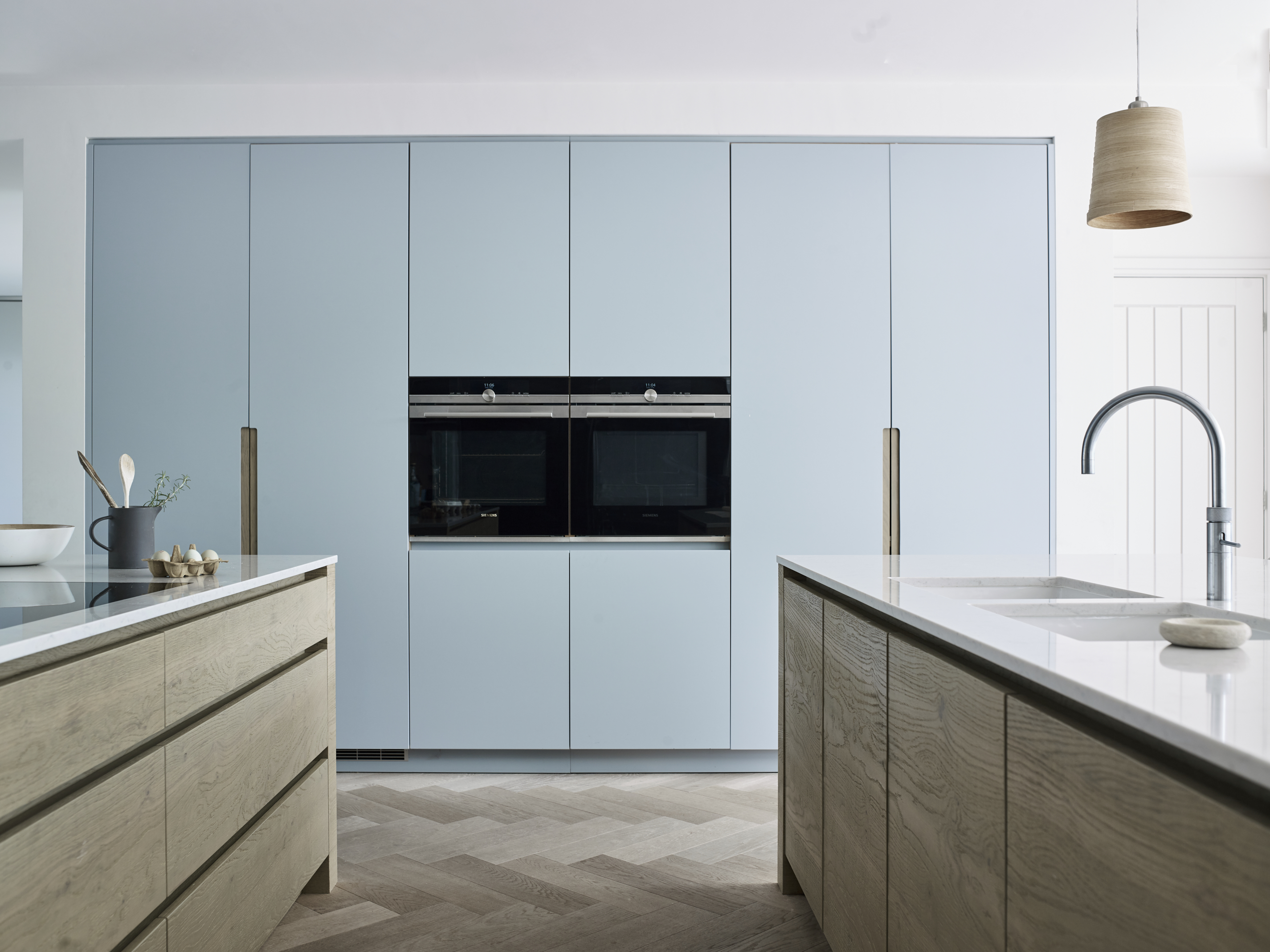 Double kitchen islands in oak with white work surfaces and light blue kitchen bespoke cabinetry