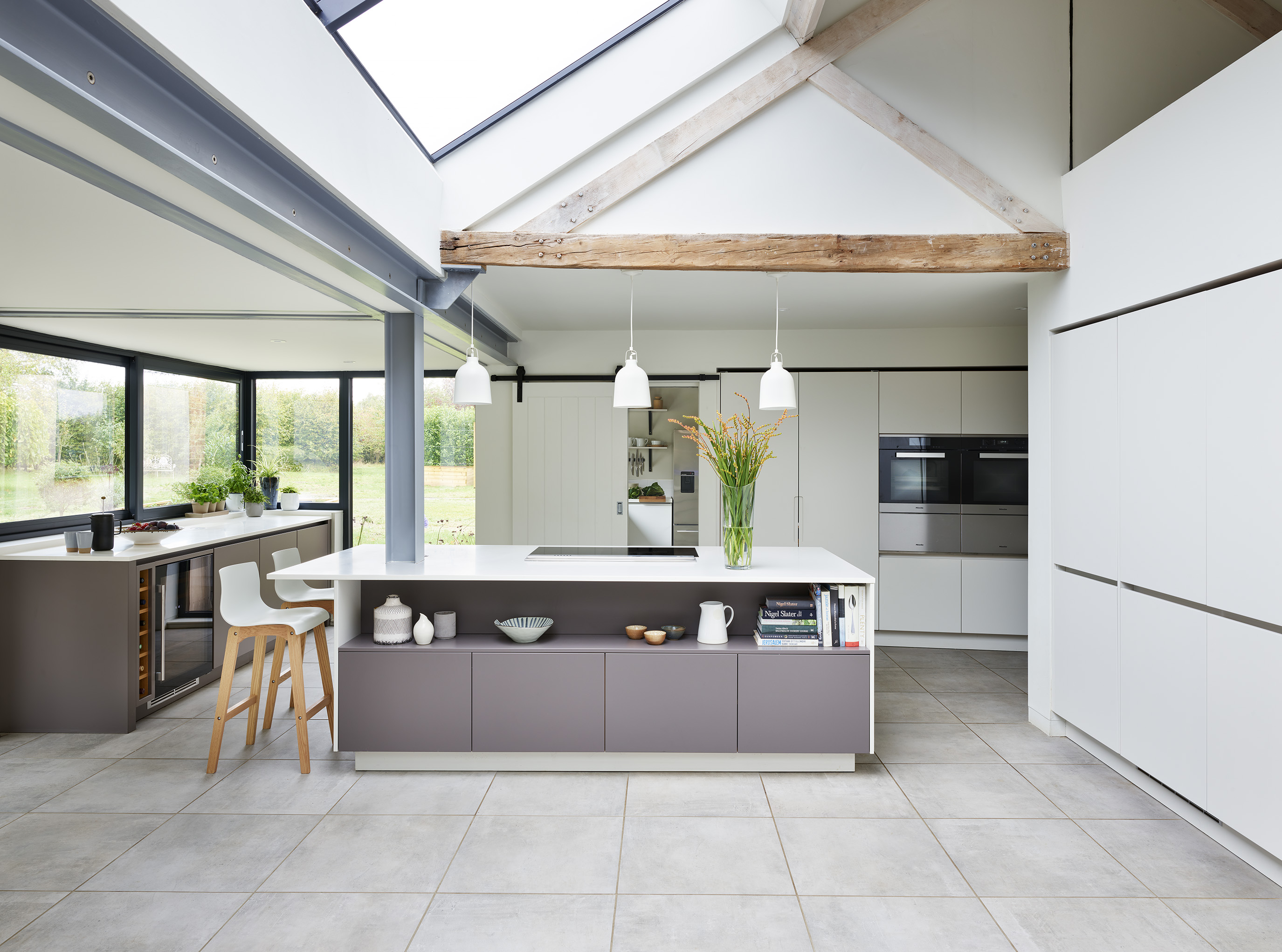 Designer kitchen by Roundhouse with kitchen lighting over island and bespoke cabinetry with white work surfaces