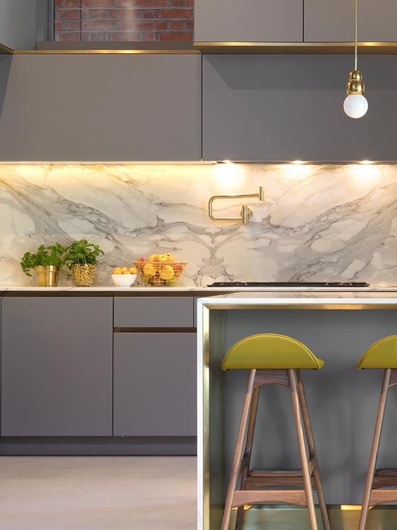 Contemporary kitchen with brass detail kitchen island and marble work surfaces