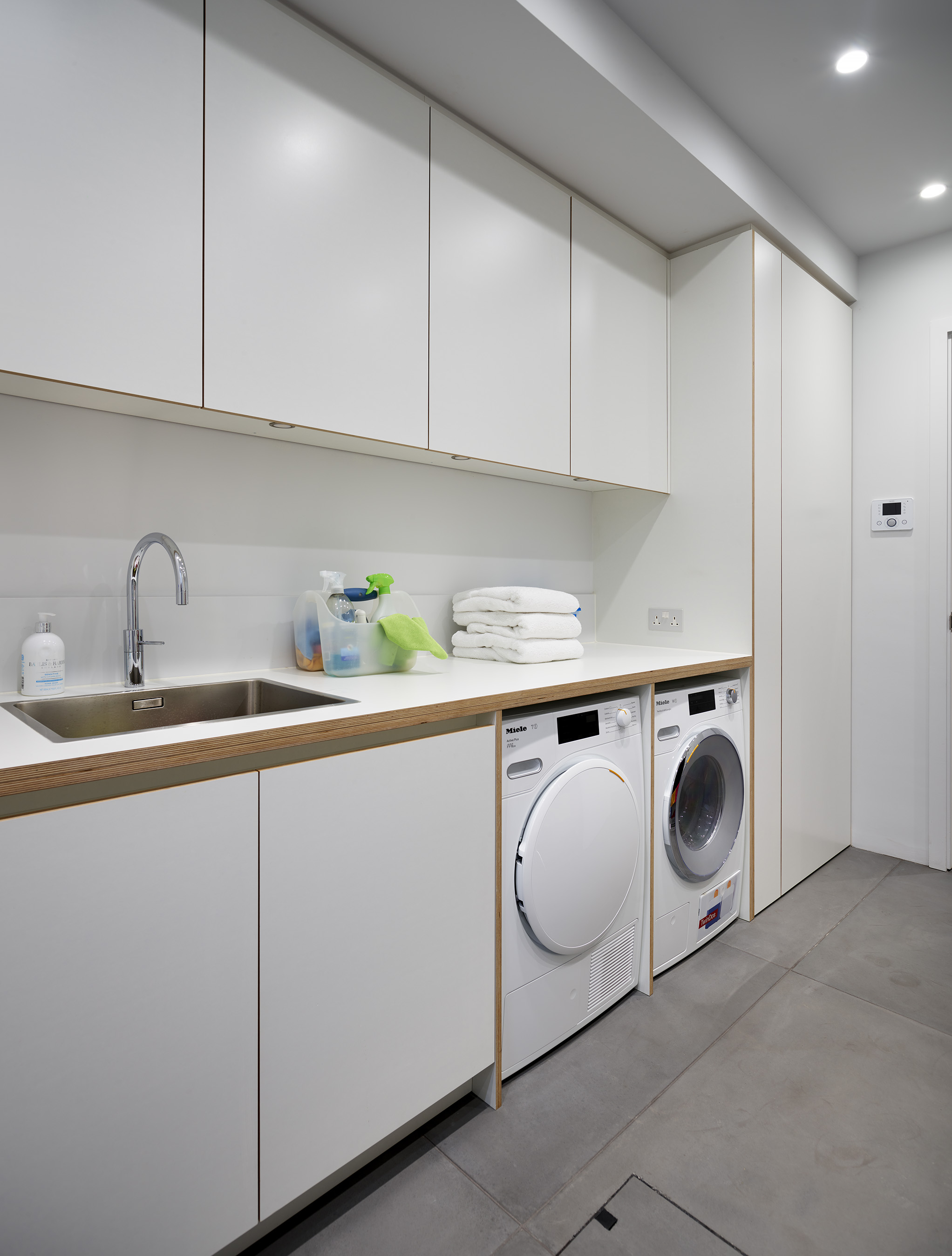 Designer bespoke furniture utility room with white cabinets and chrome sink