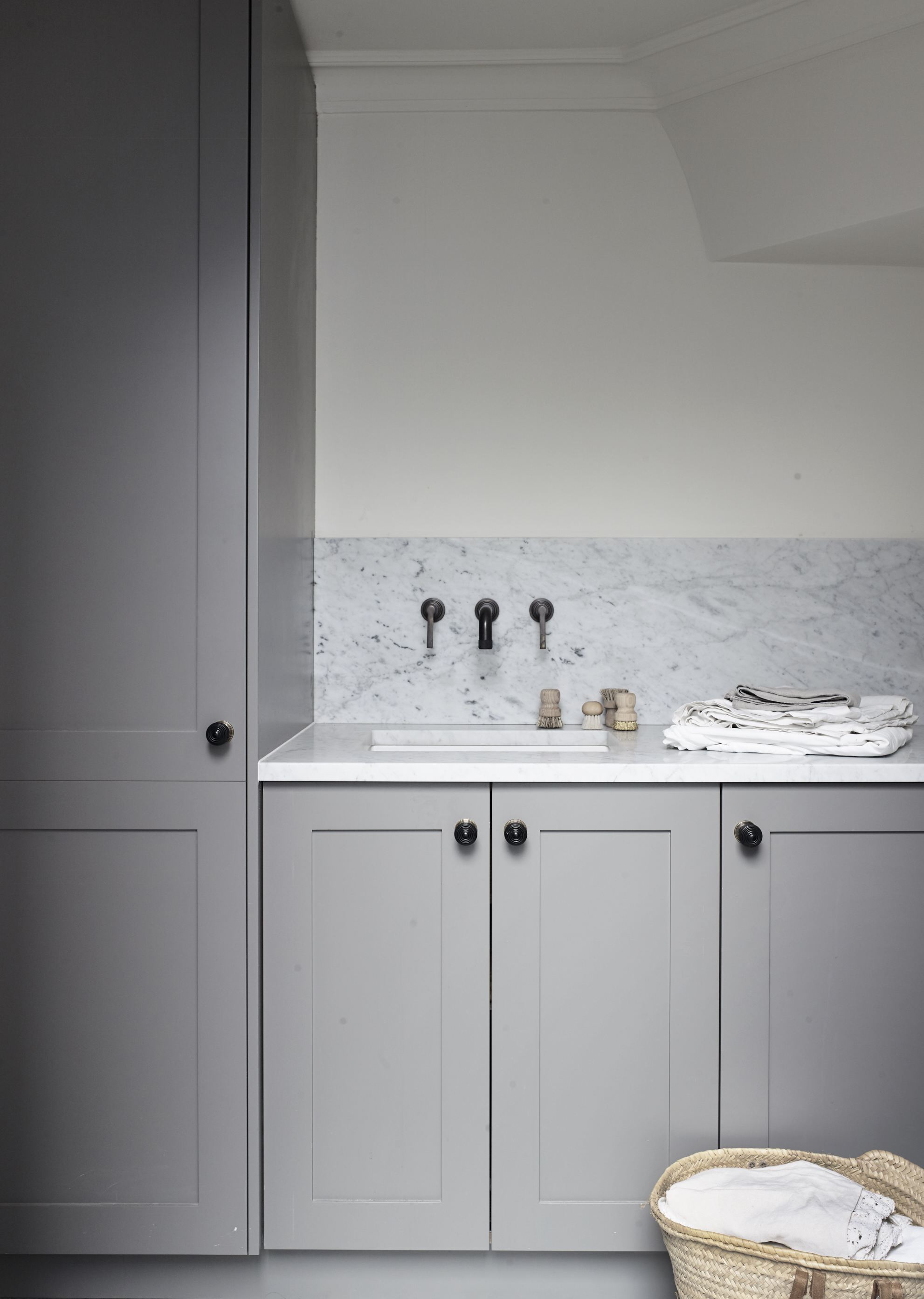 Bespoke luxury utility room in grey with marble worktop and splashback with brass handles
