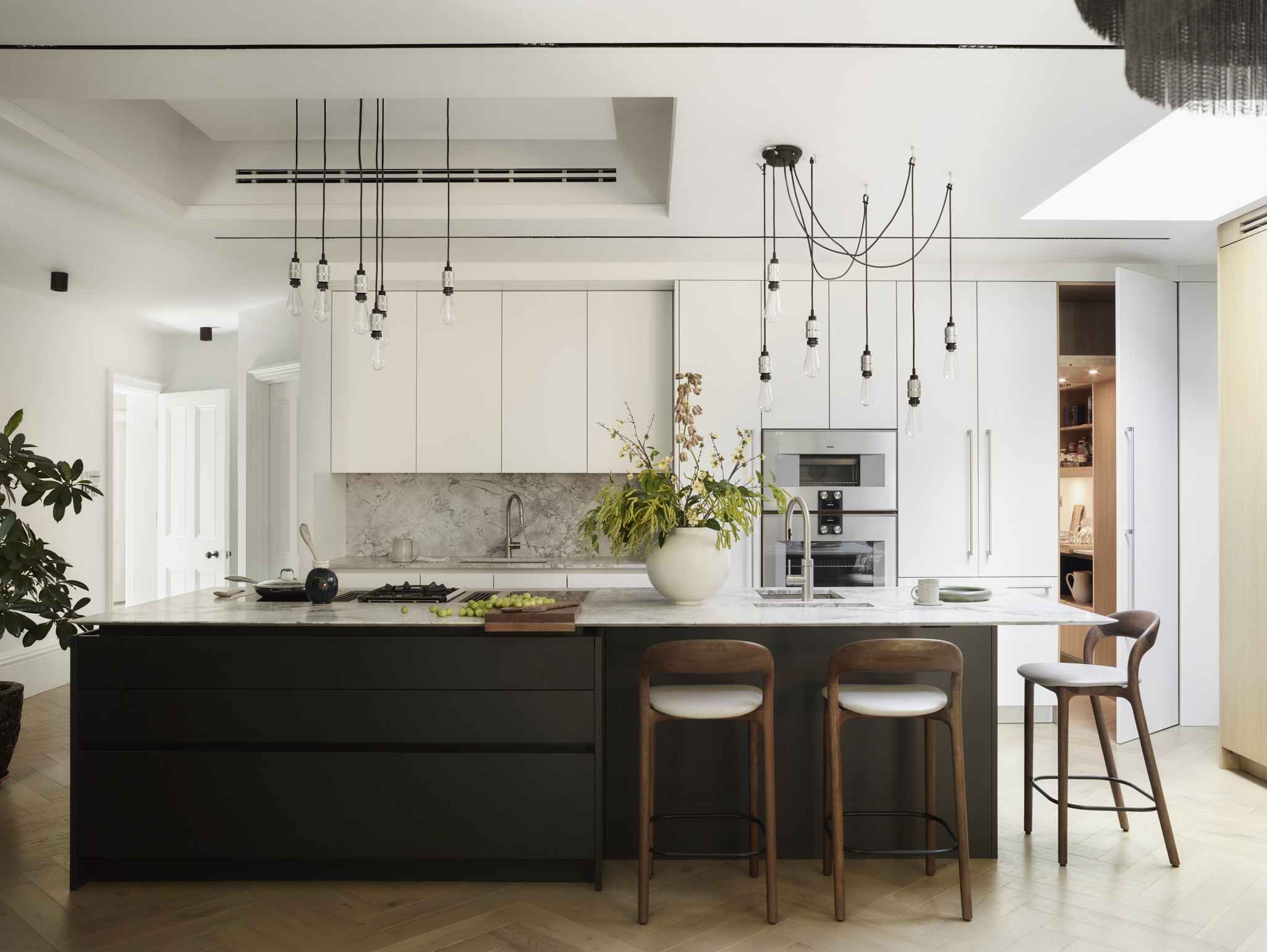 Contemporary kitchen featuring "Crafted For You" messaging with dark island, white marble worktop, dramatic clustered pendant lighting, timber bar stools, built-in appliances, and "DOWNLOAD YOUR BROCHURE" call-to-action button