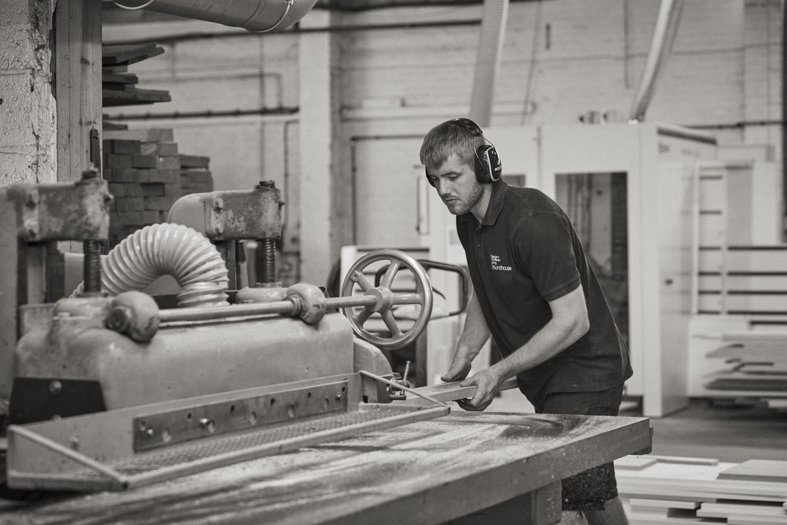 Black and white workshop scene featuring craftsman using power tool on timber with "Founded by architects, led by passion for design" heading, describing bespoke furniture creation and "EXPLORE HOW WE WORK" call-to-action