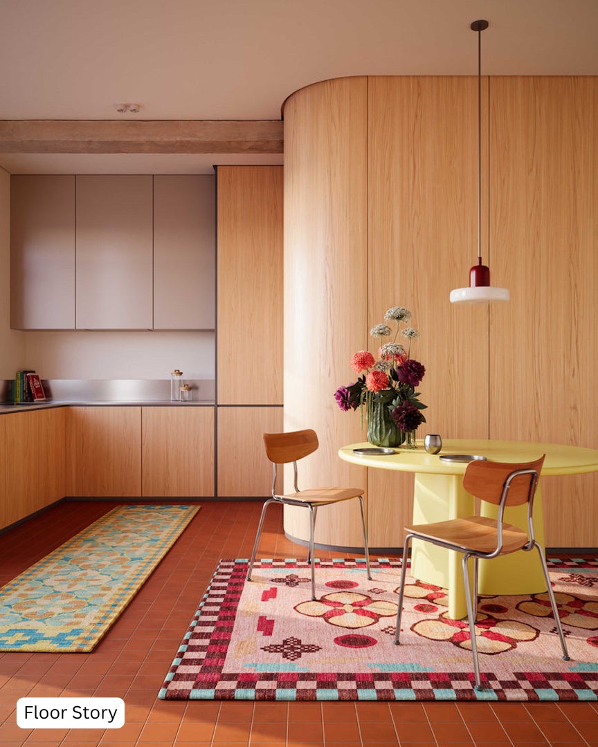 Colourful kitchen interior combining oak veneer cabinetry with curved corners, rose-grey upper units, terracotta floor tiles, chartreuse yellow dining table, vintage patterned rugs by Floor Story