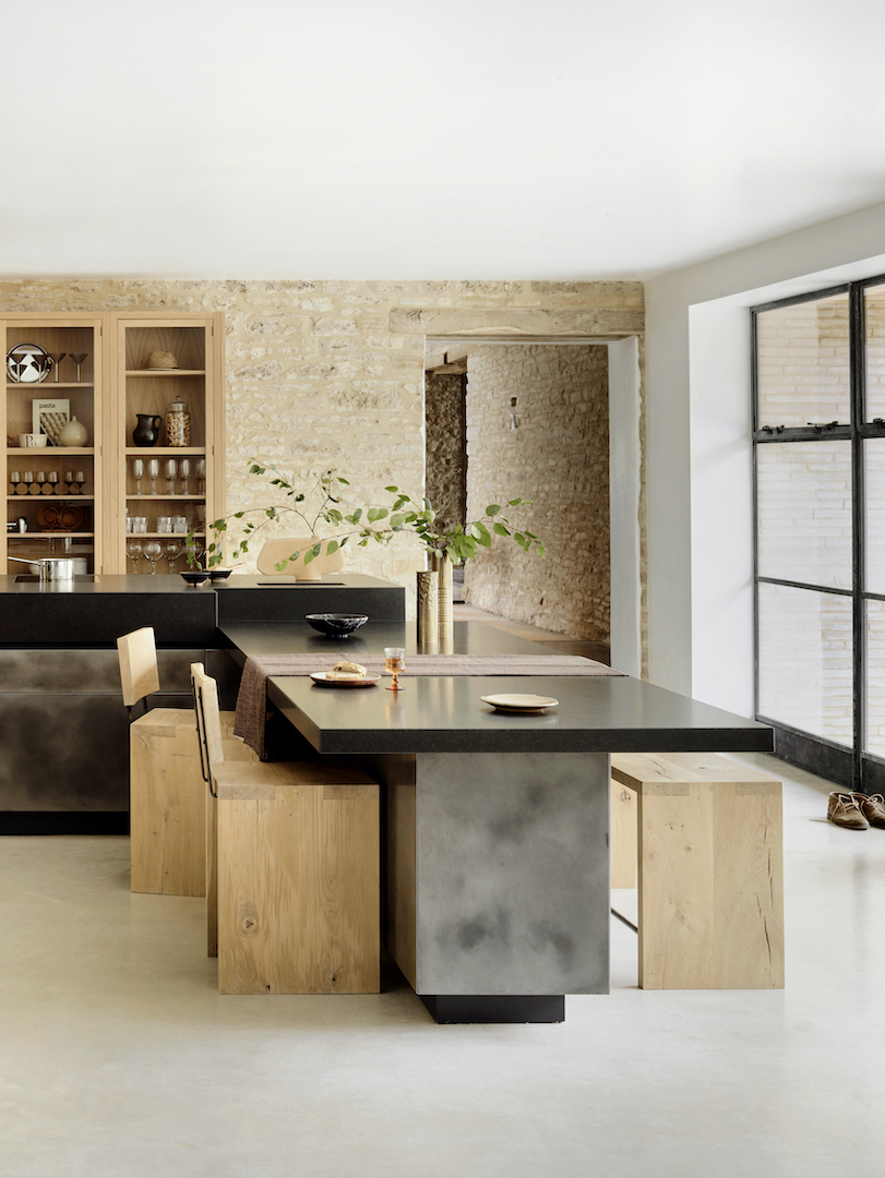 Award-winning Harding kitchen featuring black stone worktop with cantilevered breakfast bar, exposed limestone walls, oak cabinetry and Crittall-style glazed doors