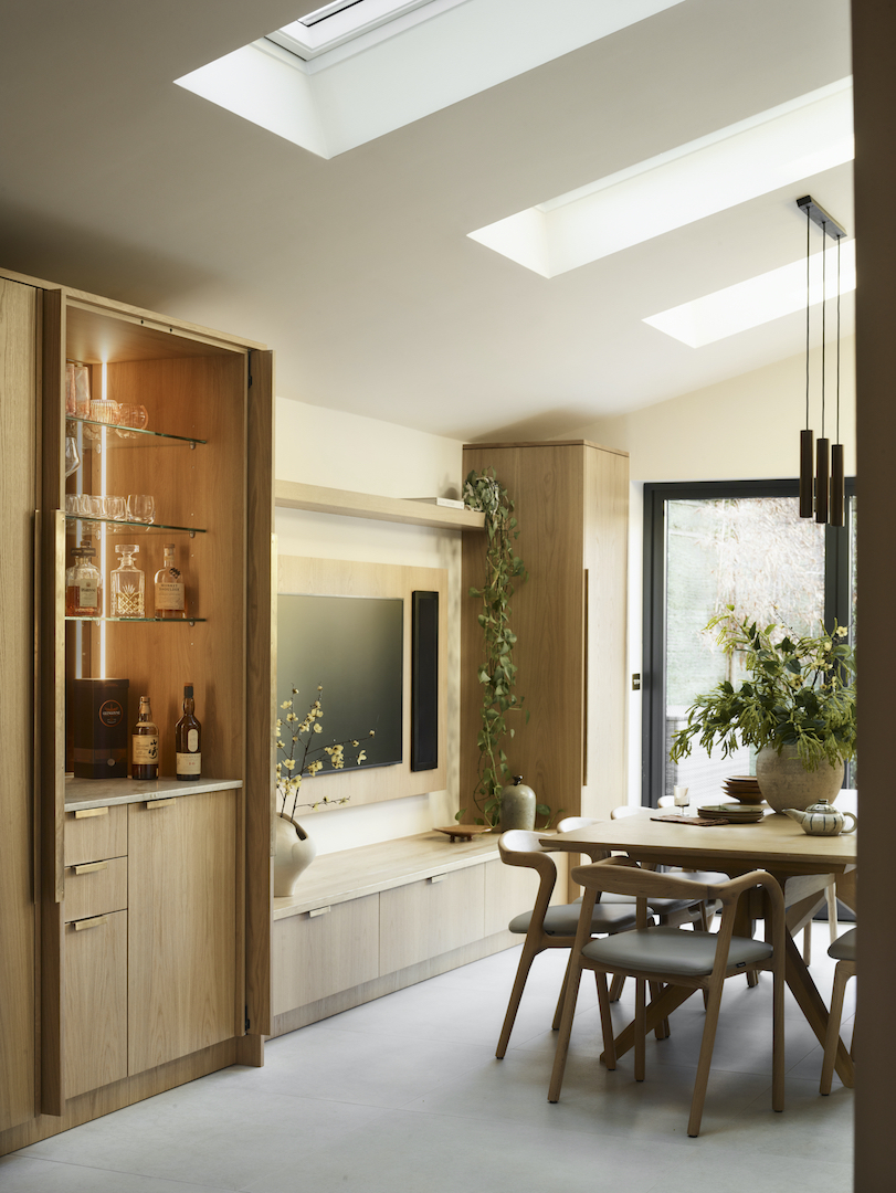 Light oak kitchen extension with integrated drinks cabinet, skylight windows, handleless cabinetry and open-plan dining area featuring natural materials