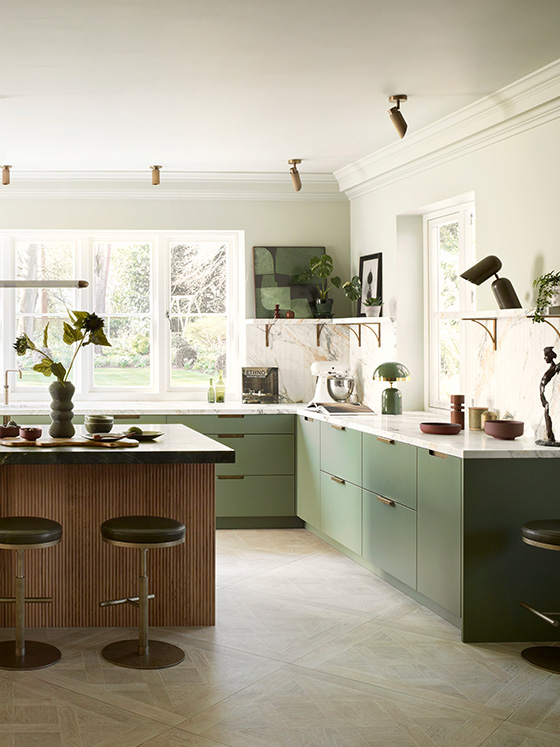 Sage green handleless kitchen with walnut fluted island, marble worktops, brass open shelving, and herringbone oak flooring in period property
