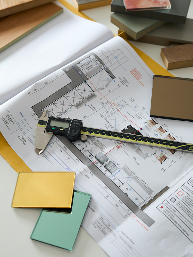 Bespoke kitchen design process showing technical floor plan with digital callipers, material samples in oak, painted finishes and stone worktop selections