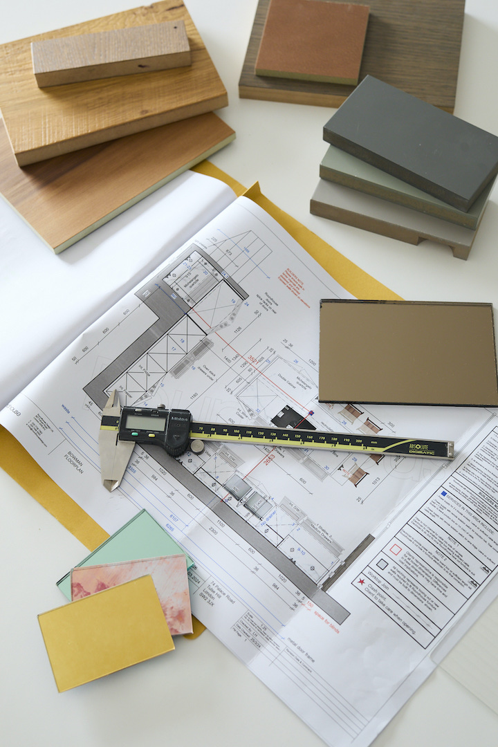 Bespoke kitchen design process showing material samples including oak veneer, painted finishes in grey and terracotta tones, technical drawings with digital caliper, and colour swatches for luxury kitchen specification