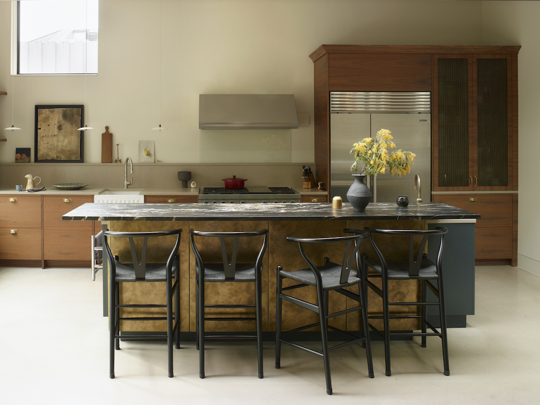 Luxury kitchen with a metal wrapped brass island, walnut cabinetry and stainless steel details in a cosy architectural interior.