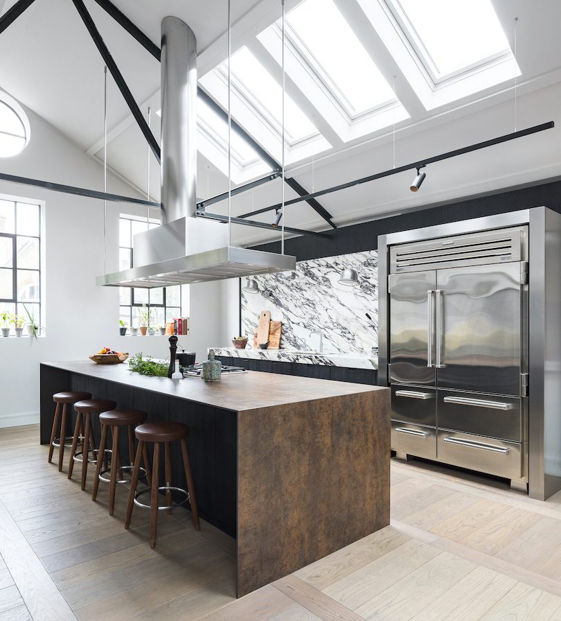 Contemporary stainless steel kitchen with industrial appliances, mixed metals and dramatic marble splashback.
