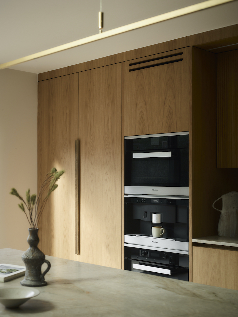 Bespoke kitchen with oak cabinetry, brass handles, stainless steel appliances and refined mixed metal details in a luxury interior.
