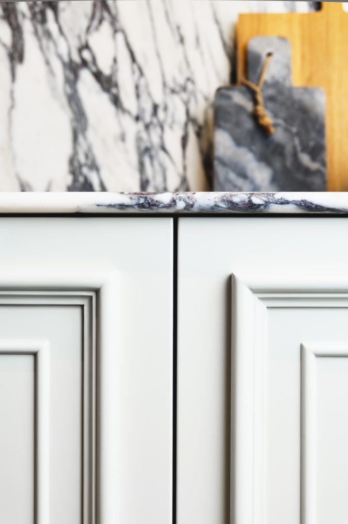 Floating fluted walnut bespoke bathroom vanity with a Calacatta marble worktop, integrated basin, black wall-mounted taps, circular mirror and contemporary wall lights at the Roundhouse + Day True Wimbledon showroom.