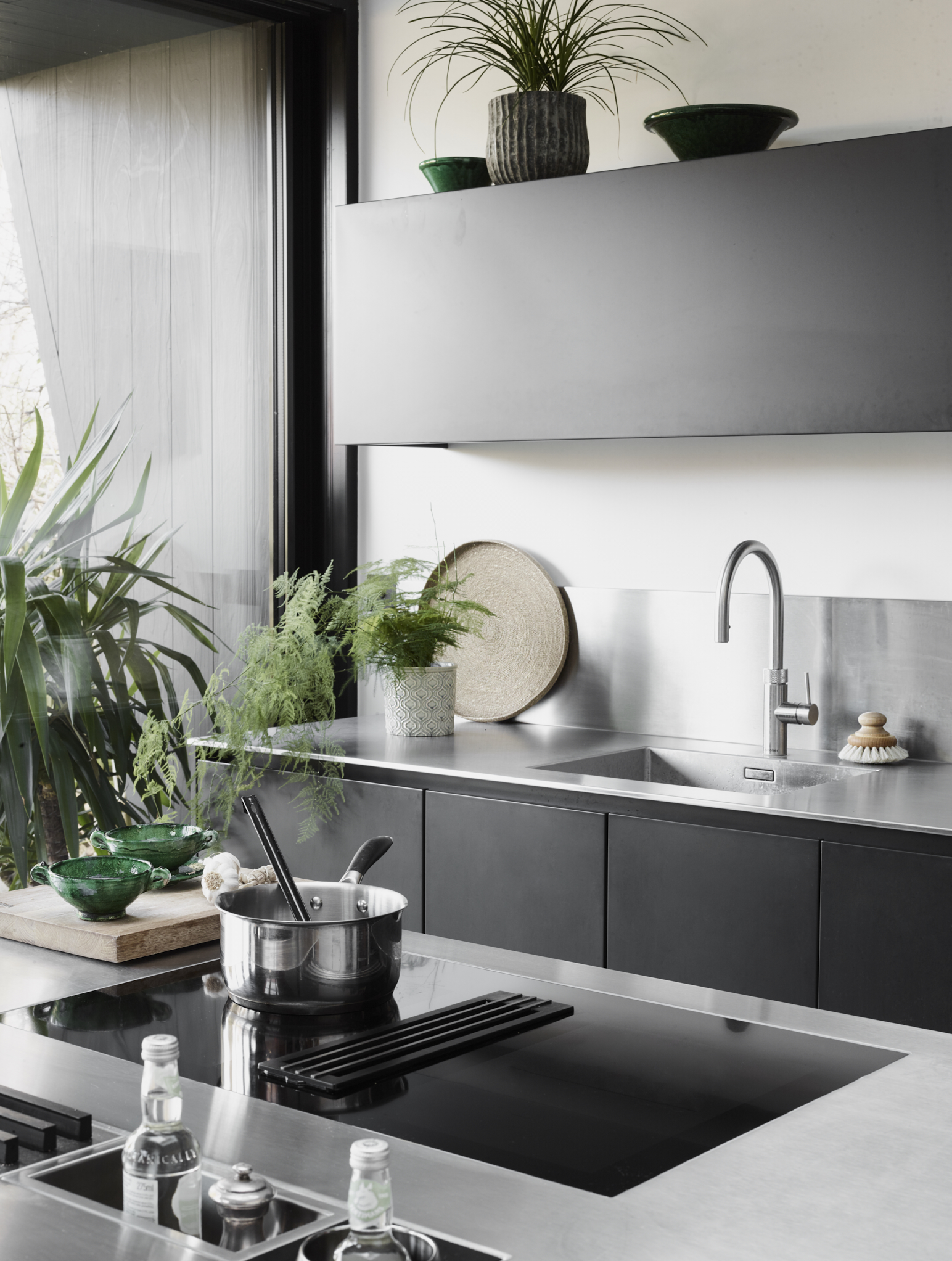 Contemporary stainless steel kitchen with black handleless cabinetry, stainless steel worktops and minimalist architectural design.