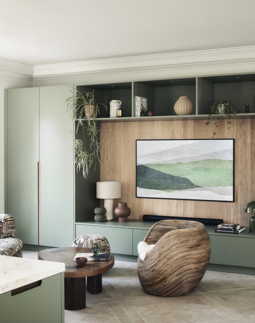 Bespoke fitted living room cabinetry in sage green with fluted oak panelling, open shelving and contemporary interior styling. Creates a calming atmosphere inspired by nature and biophilic design.