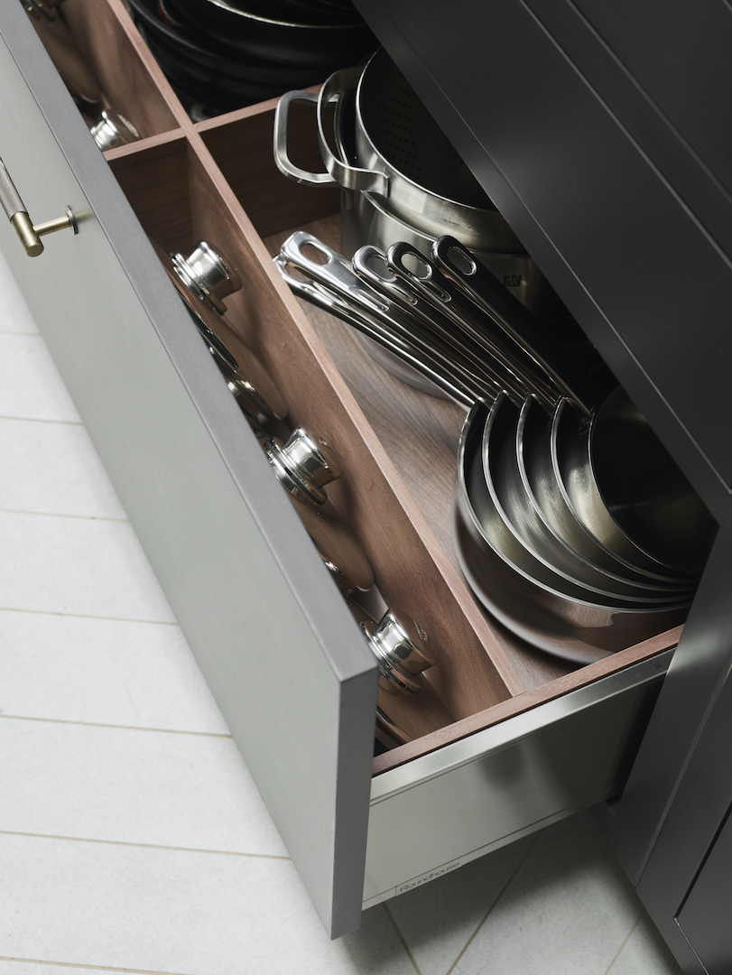 Bespoke kitchen storage drawer with timber dividers organising stainless steel pans and cookware.