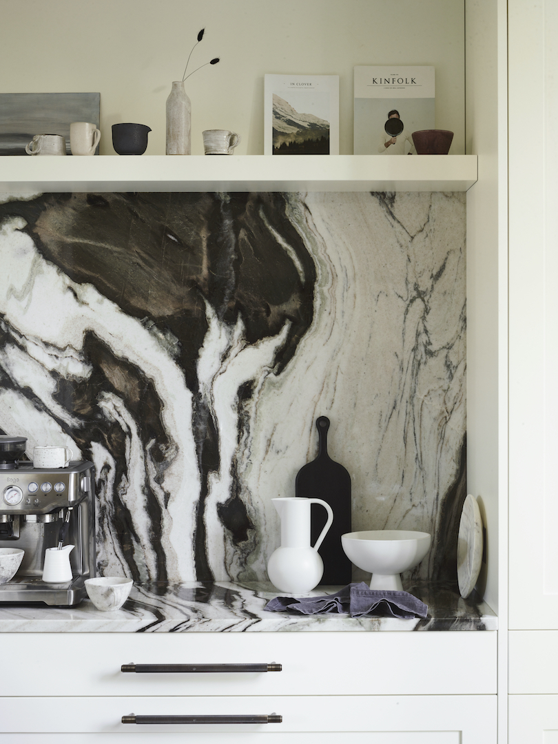 Close up of San Simone quartzite splashback and worktops with open shelving in this monochrome white kitchen featuring classic framed cabinetry.