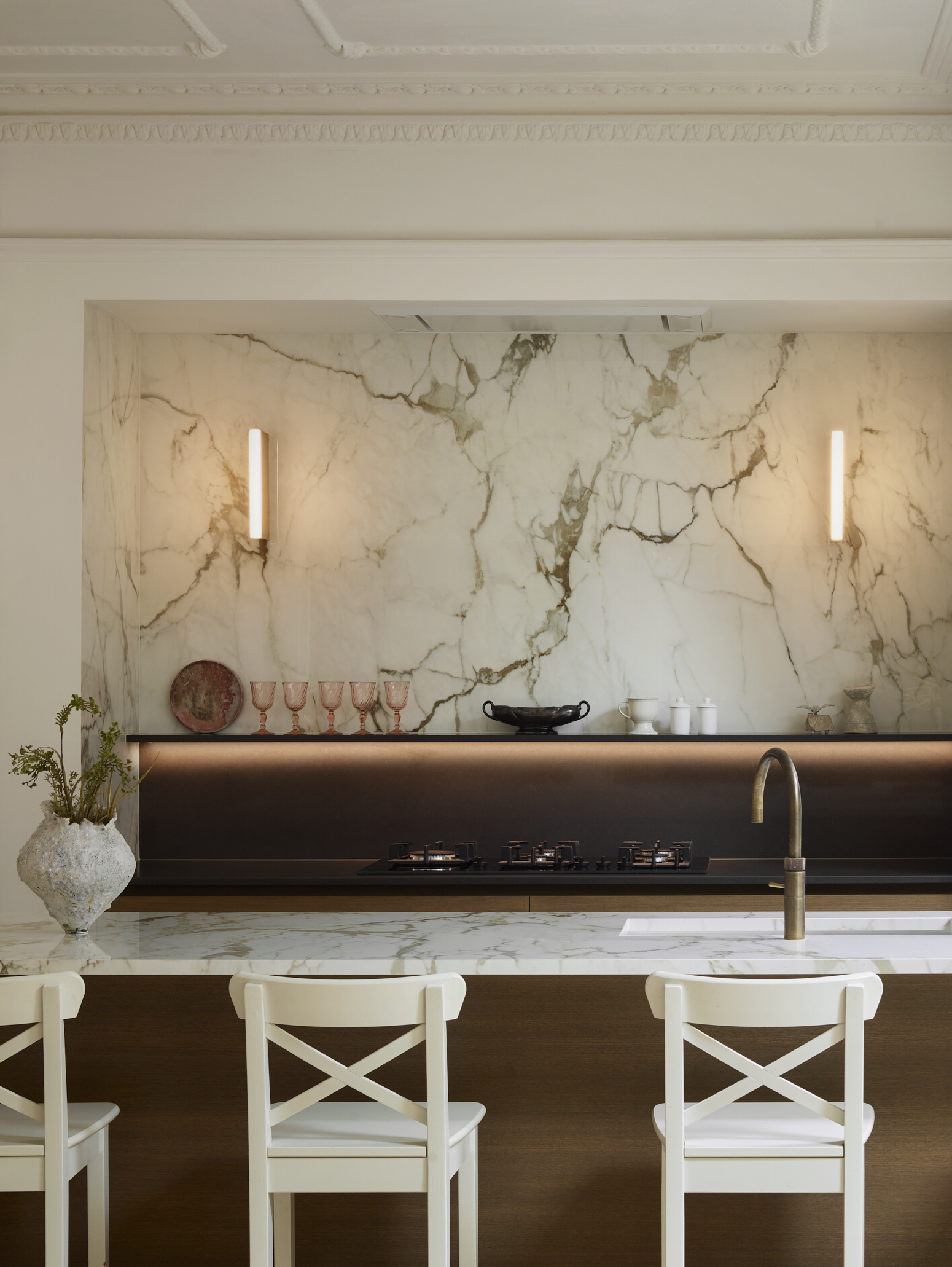 Luxury bespoke kitchen featuring a statement marble splashback, layered lighting and warm timber cabinetry, bringing softness and timeless elegance to contemporary kitchen design.