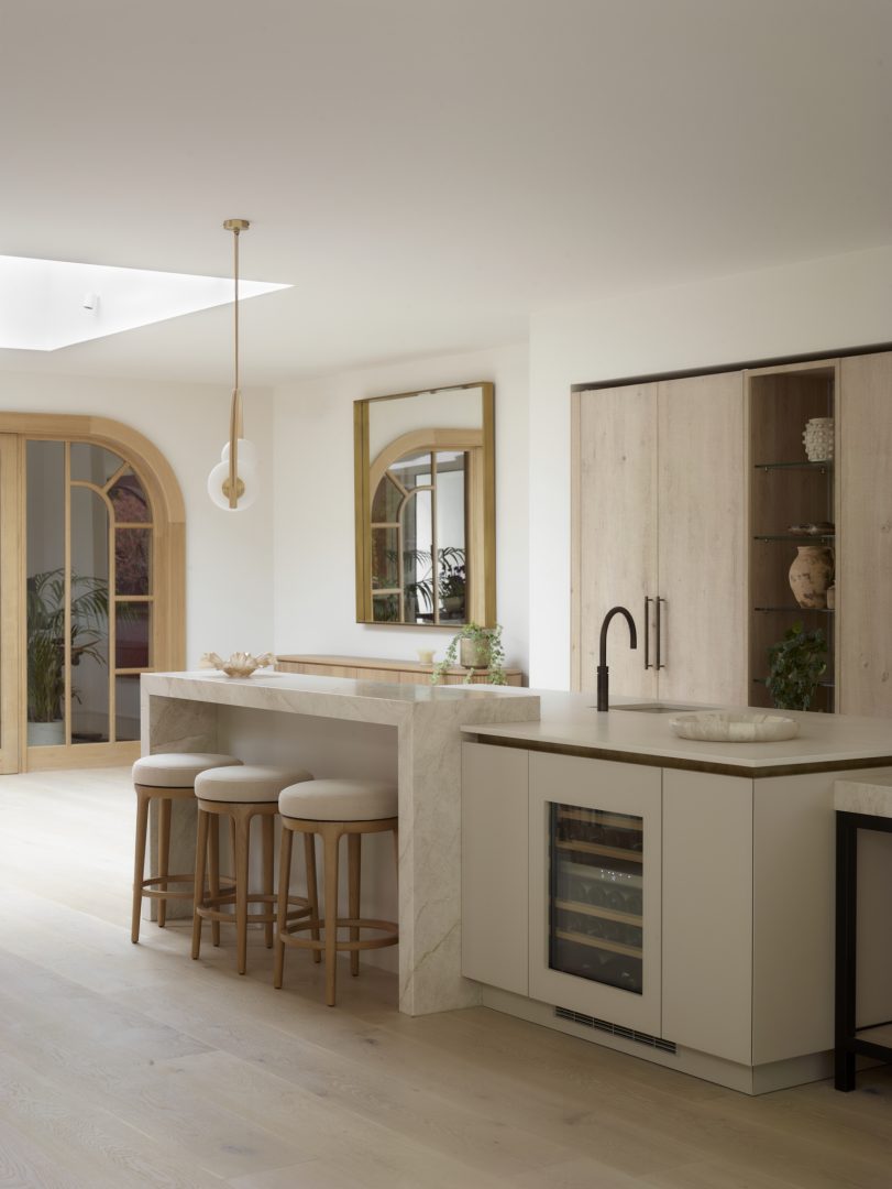 Bespoke kitchen island with waterfall quartzite breakfast bar, matt lacquer cabinetry, integrated wine fridge and rough sawn oak furniture by Roundhouse Design.