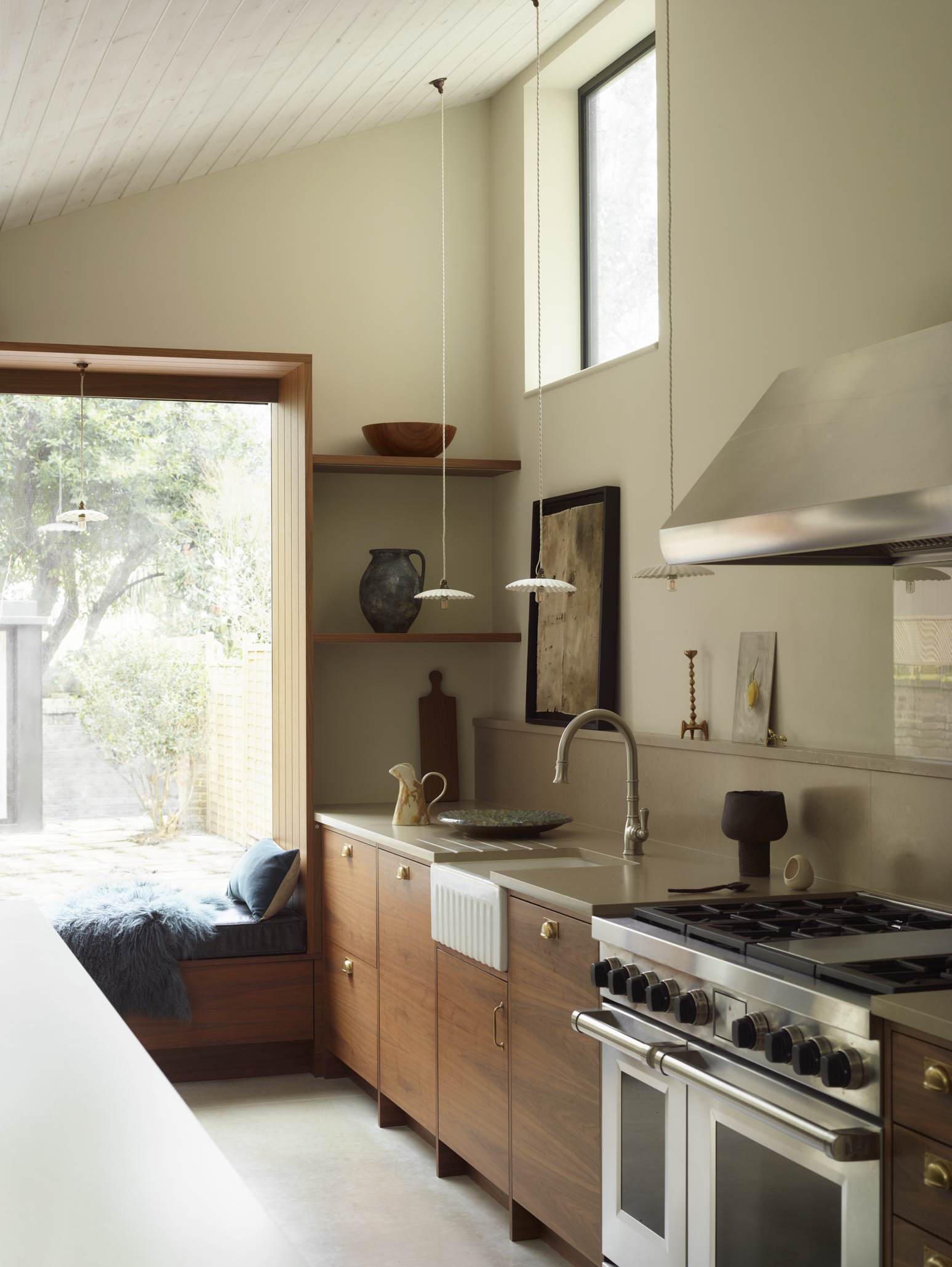 Soft kitchen design featuring bespoke banquette seating beneath a window, natural timber cabinetry and layered textures for relaxed family living.