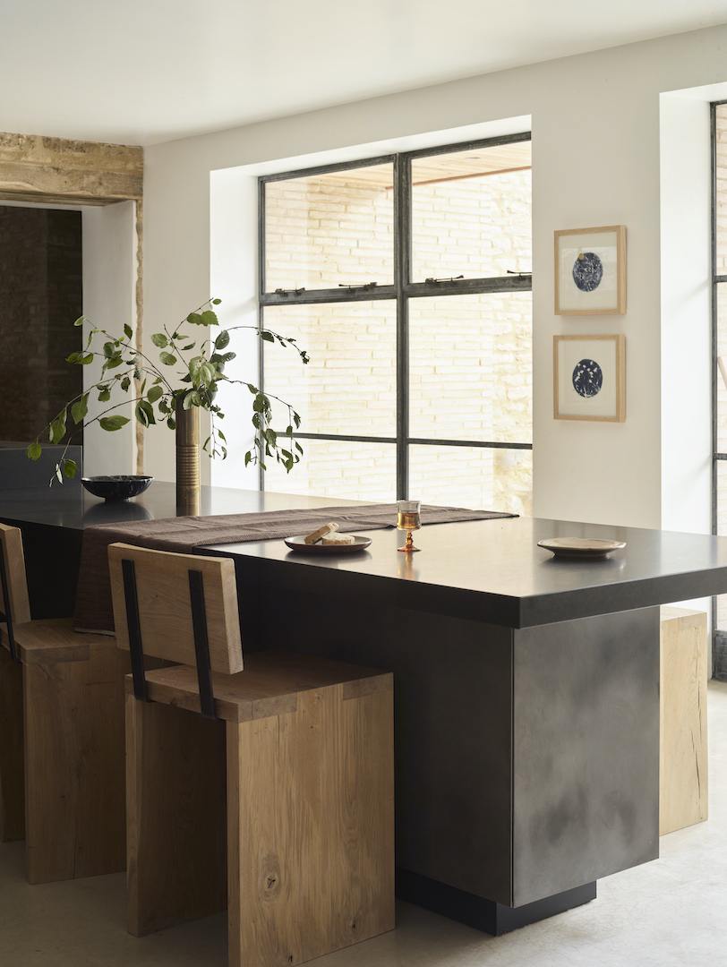 Bespoke kitchen island with integrated dining, timber seating and dark metal cabinetry by Roundhouse
