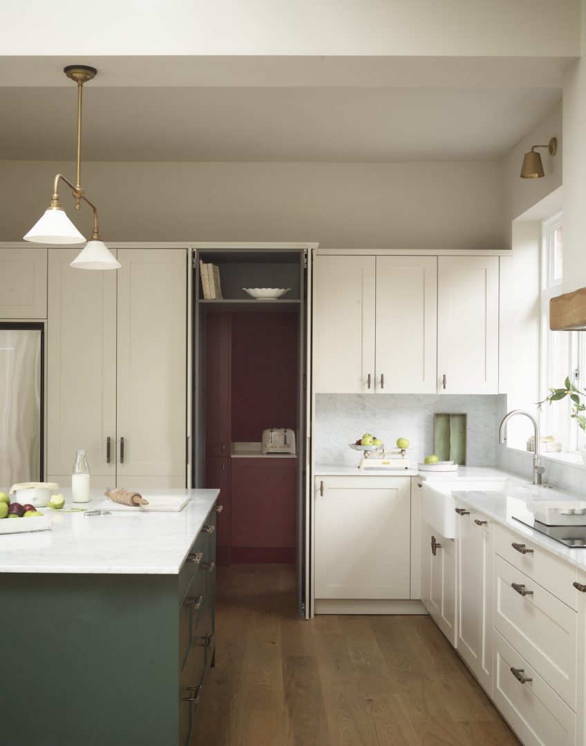 Pocket doors opening to reveal a hidden utility room with bespoke storage concealed behind kitchen cabinetry.