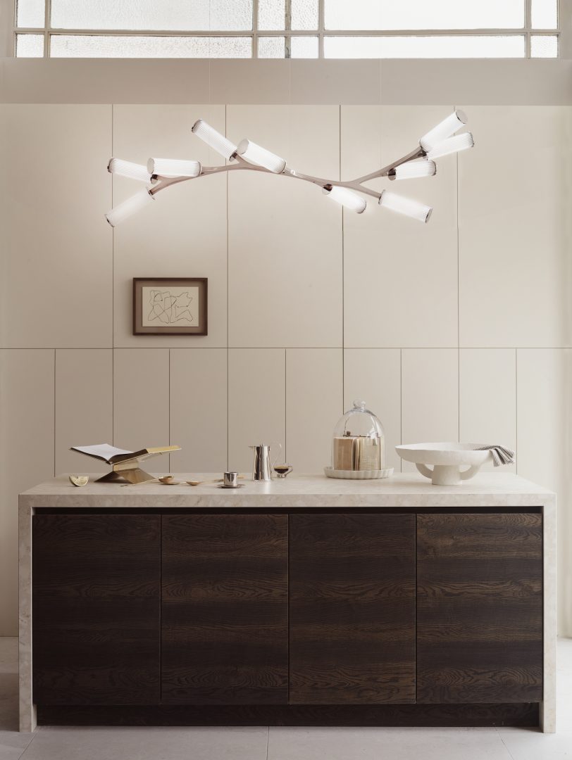 Contemporary kitchen with dark wood cabinetry, pale stone worktop and sculptural branching ceiling light with sculptural lighting.