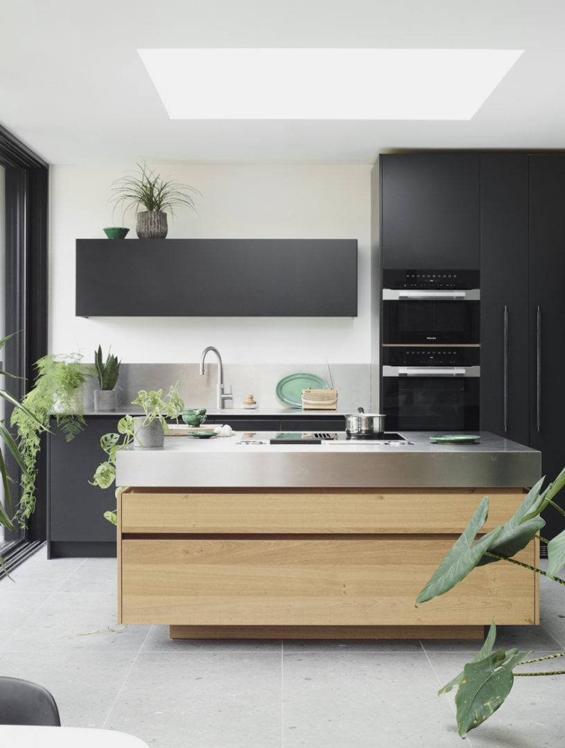 Contemporary black and timber kitchen with a stainless steel island worktop and integrated hob