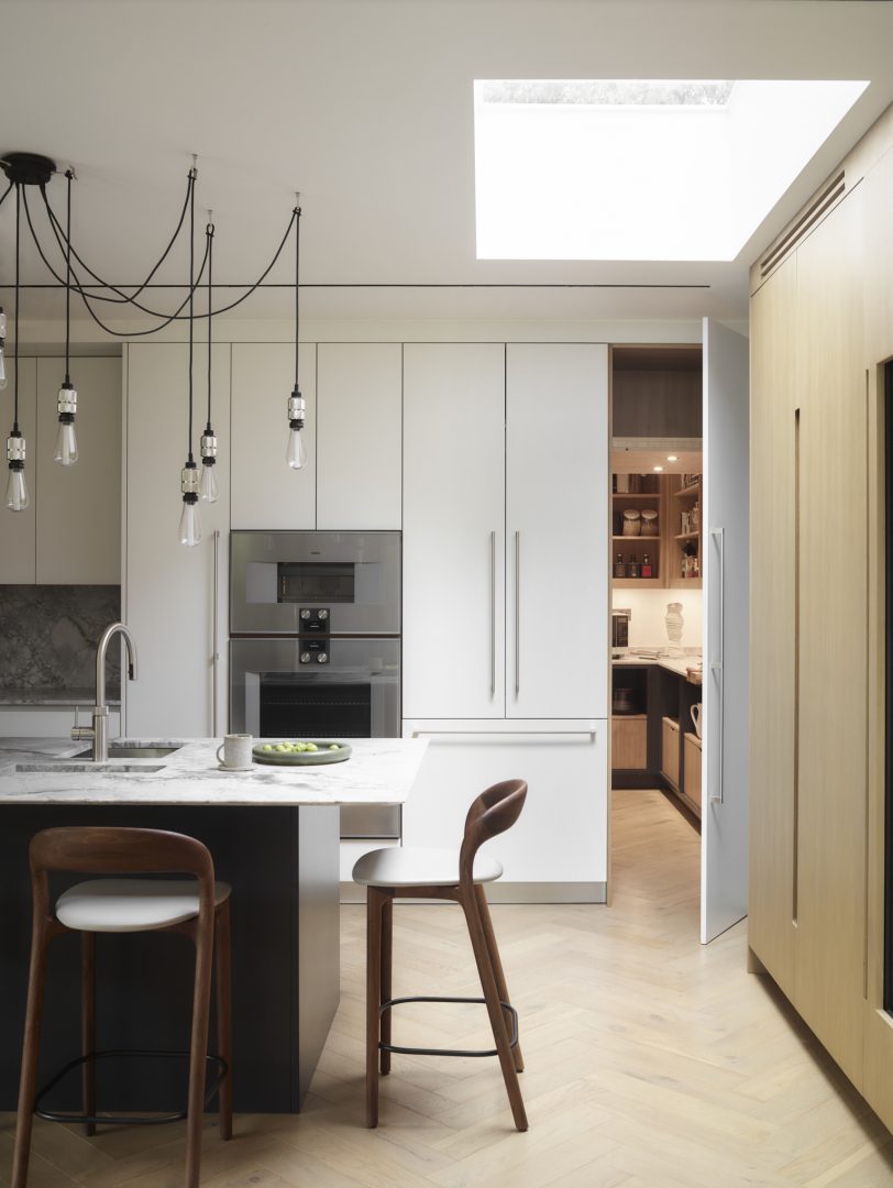 Hidden walk-in pantry concealed behind integrated kitchen cabinetry, creating a clean and uncluttered bespoke kitchen.