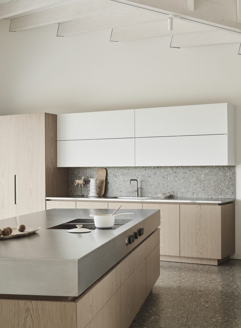 Contemporary timber kitchen with a large grey stone island worktop and terrazzo splashback