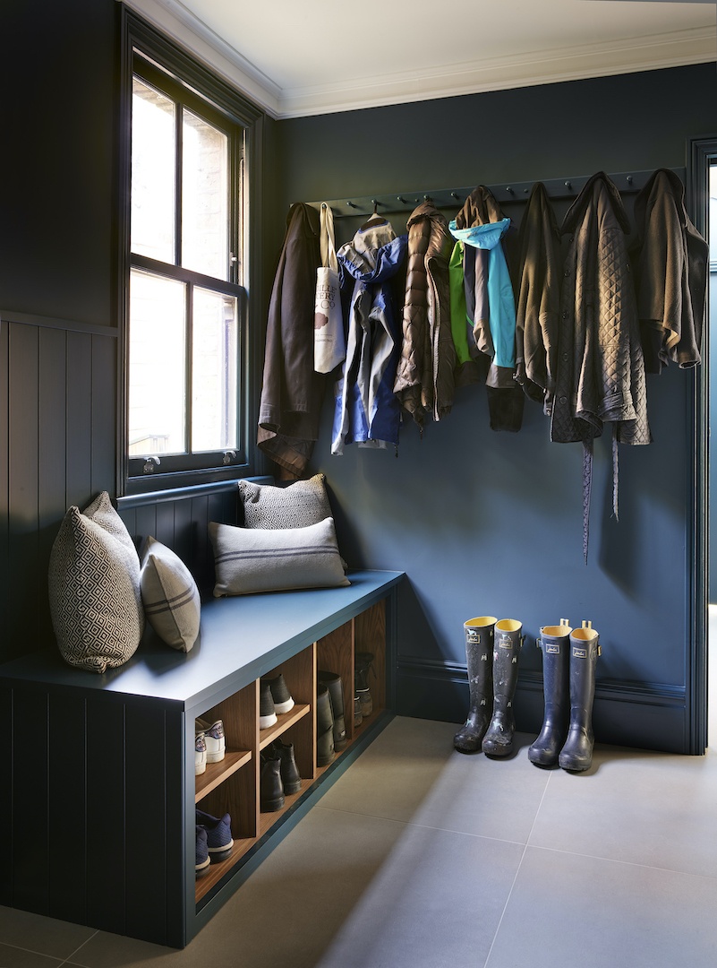 Dark blue boot room with built-in bench seating, coat hooks and open oak shoe storage