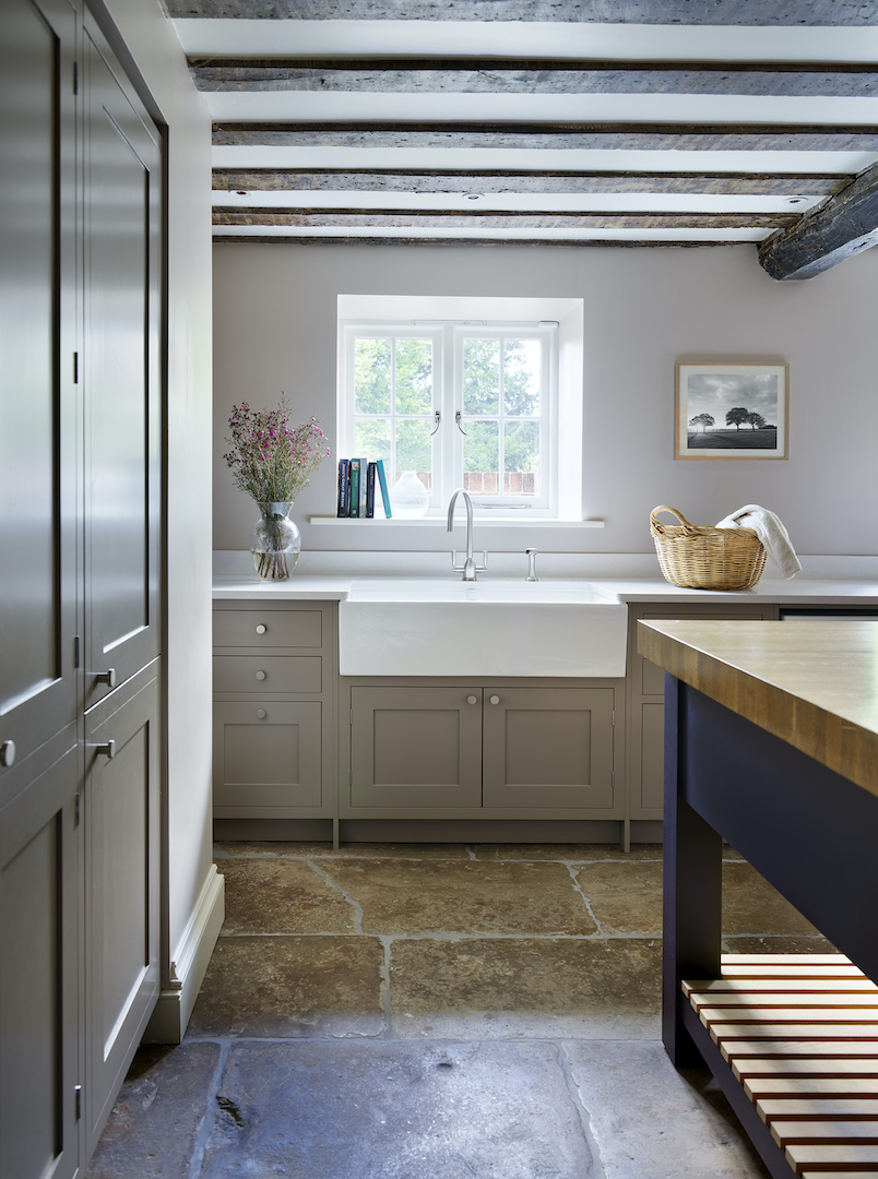 Traditional boot room with beige painted cabinetry, farmhouse sink, stone flooring and timber-topped navy island