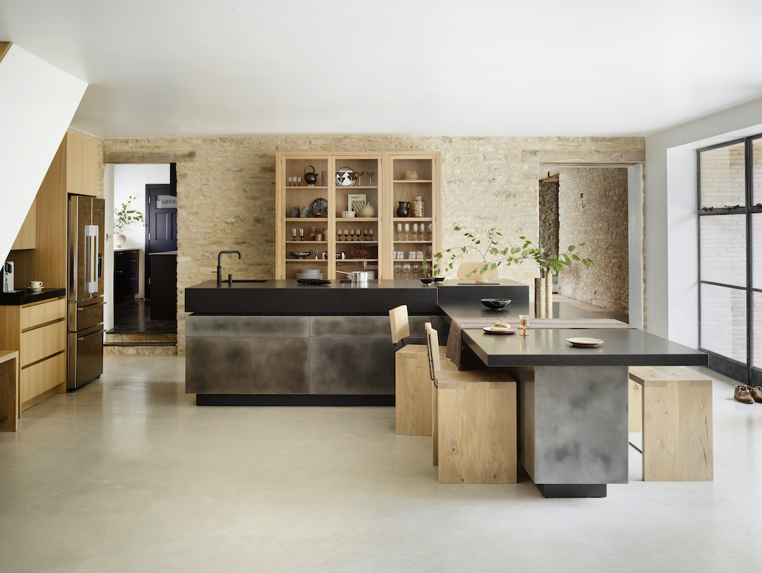 Bespoke kitchen island with a perpendicular dining table, metal-wrapped cabinetry and timber seating in a contemporary open-plan kitchen.