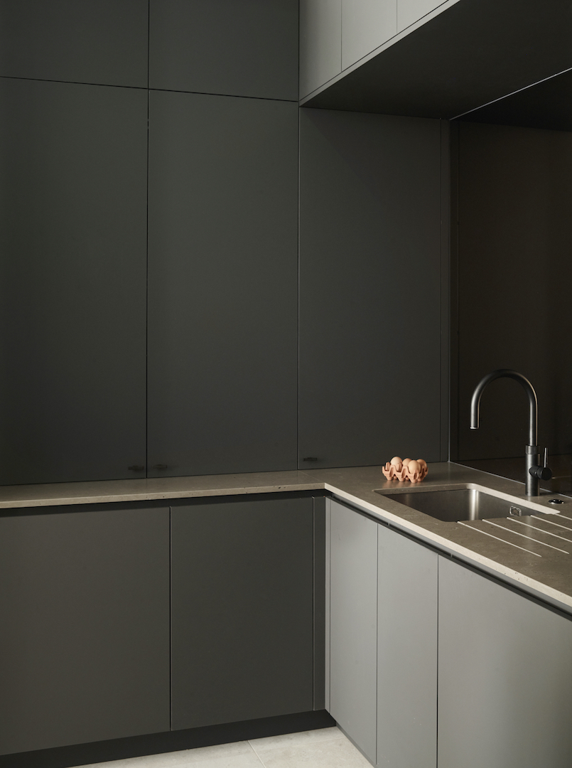Contemporary utility and boot room with dark handleless cabinetry, stainless steel sink and durable worktop