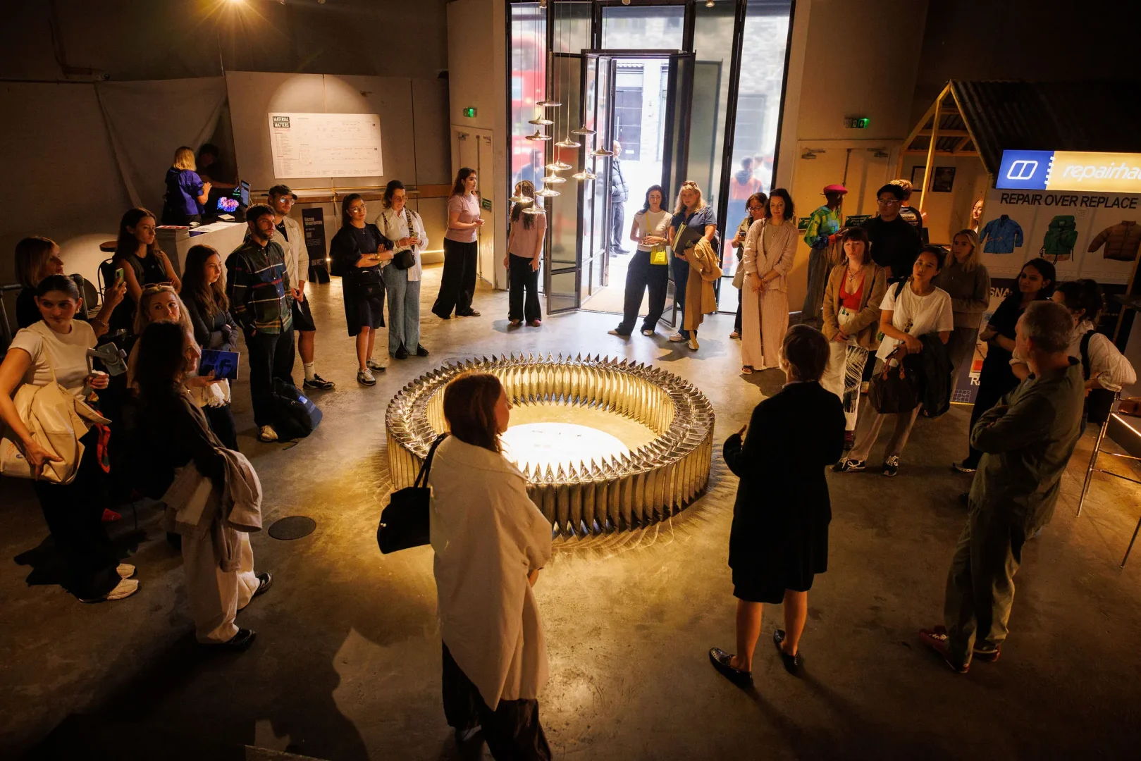 Visitors gathered around a circular illuminated installation at Material Matters during Shoreditch Design Week 2026.