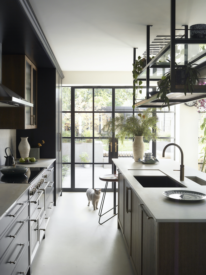 Bespoke Roundhouse Munro kitchen with suspended black metal shelving above the island, complementing the Crittall-style glazed doors and dark cabinetry.
