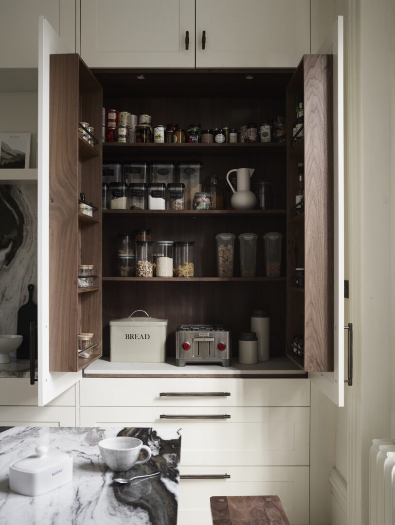 Bespoke kitchen pantry with open walnut interior, organised shelving, integrated storage and concealed small appliances.
