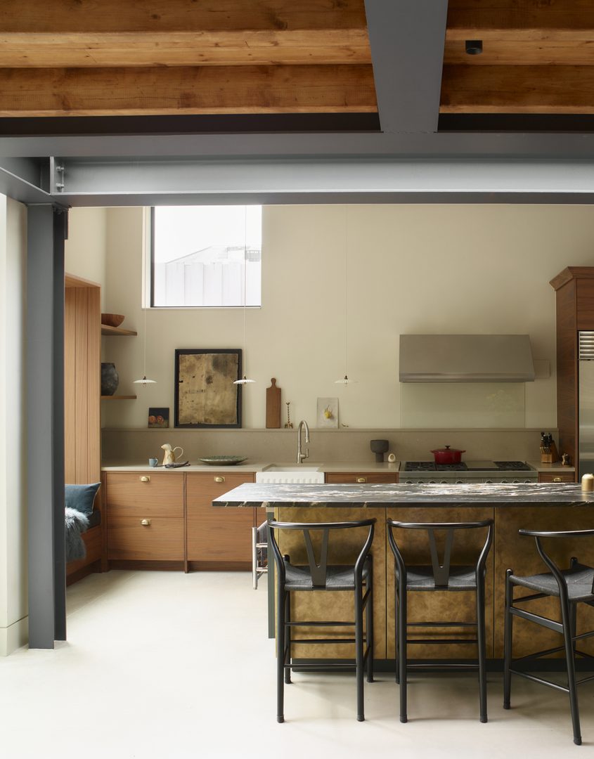 Award-winning Roundhouse Moony kitchen featuring warm walnut cabinetry, a brass-toned island, exposed timber beams and a naturally layered material palette.